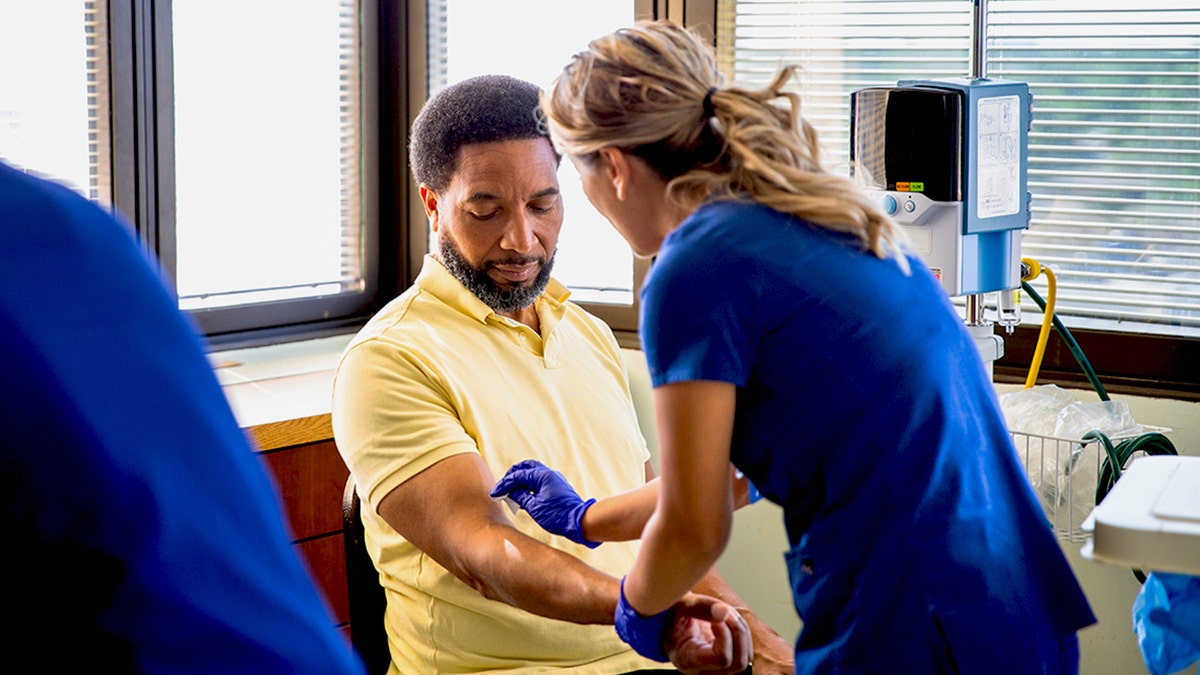 Man having his blood drawn by a female nurse in a hospital.