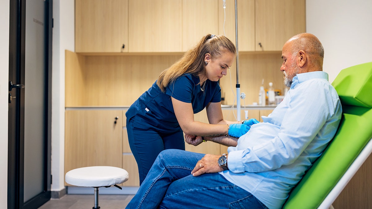 Focused nurse pierces the patient's arm vein with needle blank tube