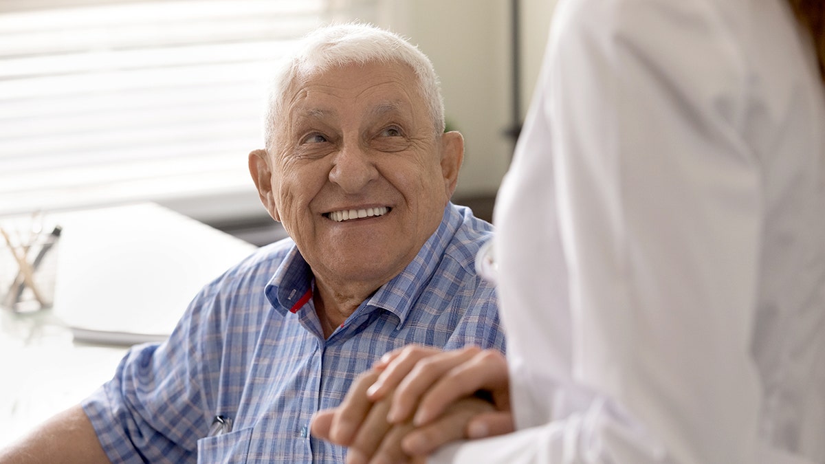 Man and caregiver wearing white uniform holding hands