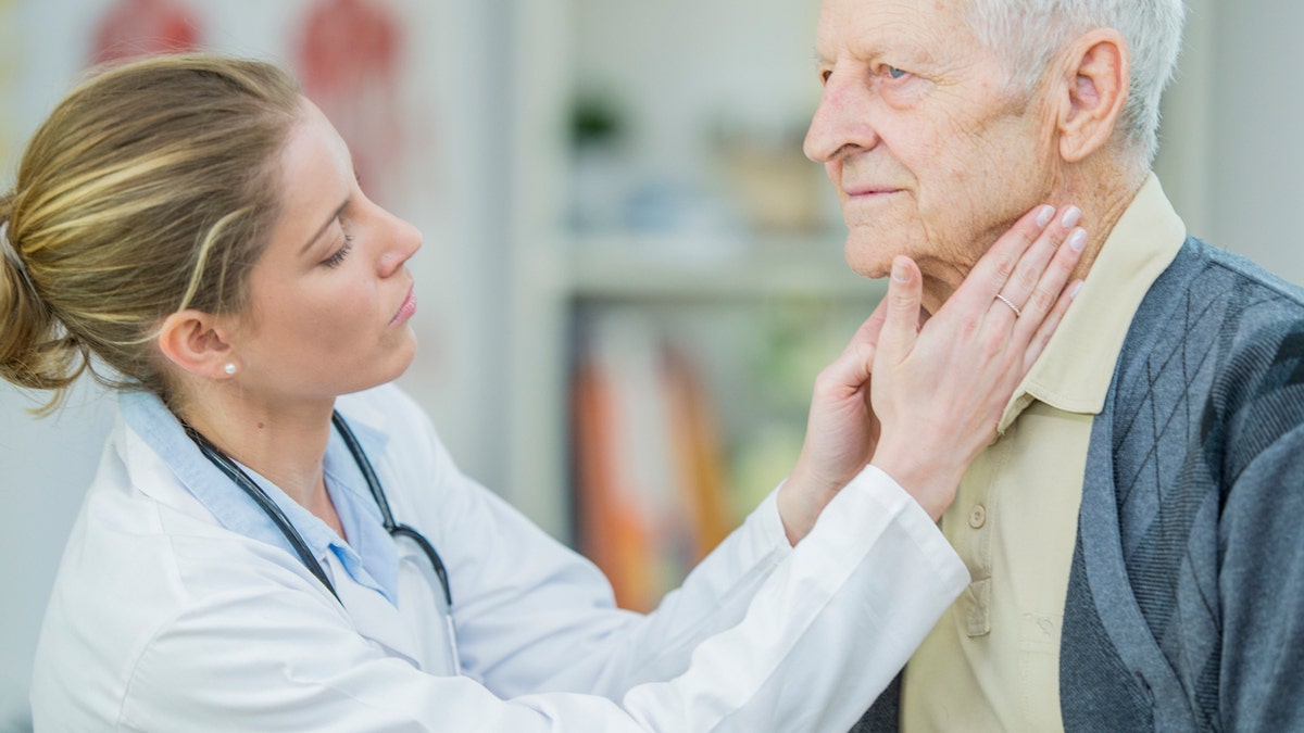 Doctor checking older mans thyroid gland