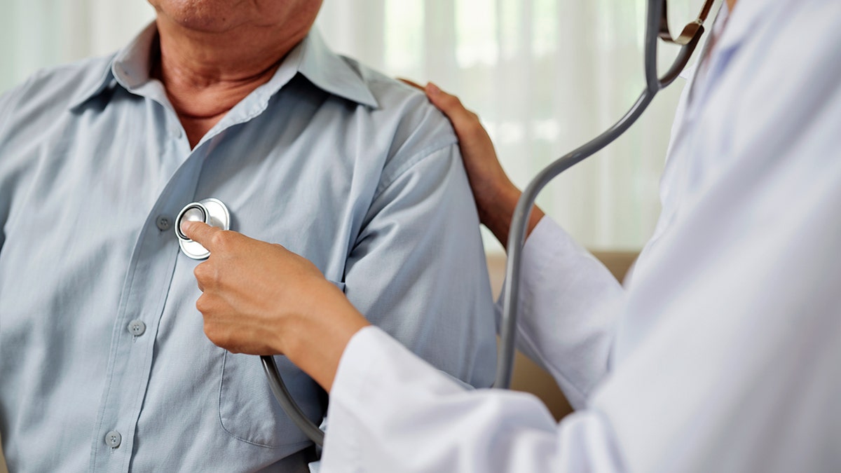 Close-up of doctor in white coat listening to breathing of senior man