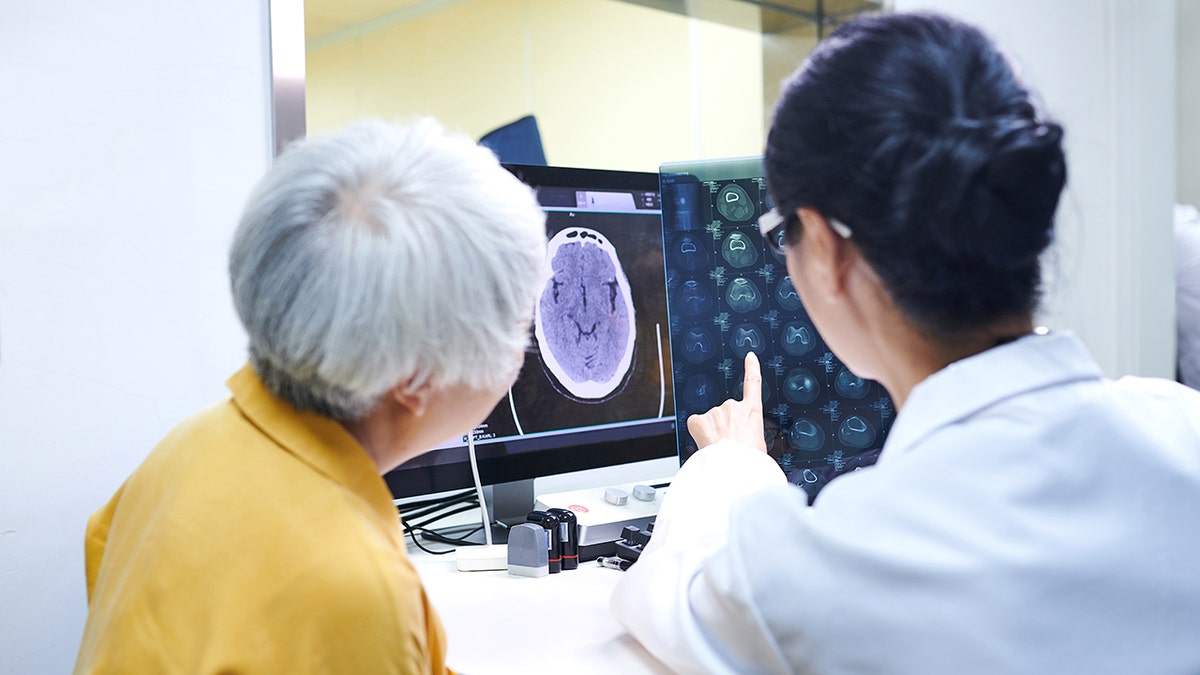 doctor points to MRI brain scan with patient