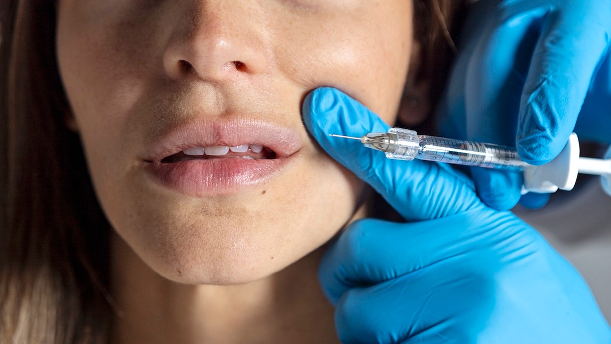 Woman being injected with cosmetic filler by doctor