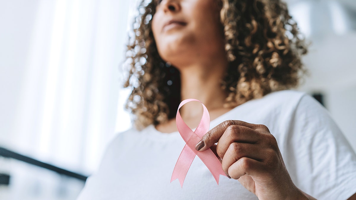 Woman holds breast cancer ribbon