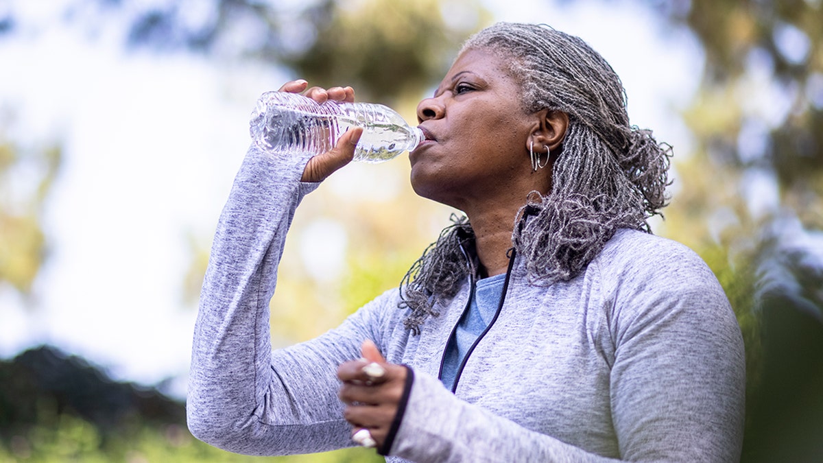woman drinks water from plastic bottle